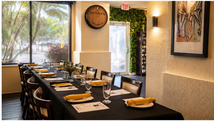 Private event table set with plates, glasses and Santa Alicia barrel decoration on the wall.