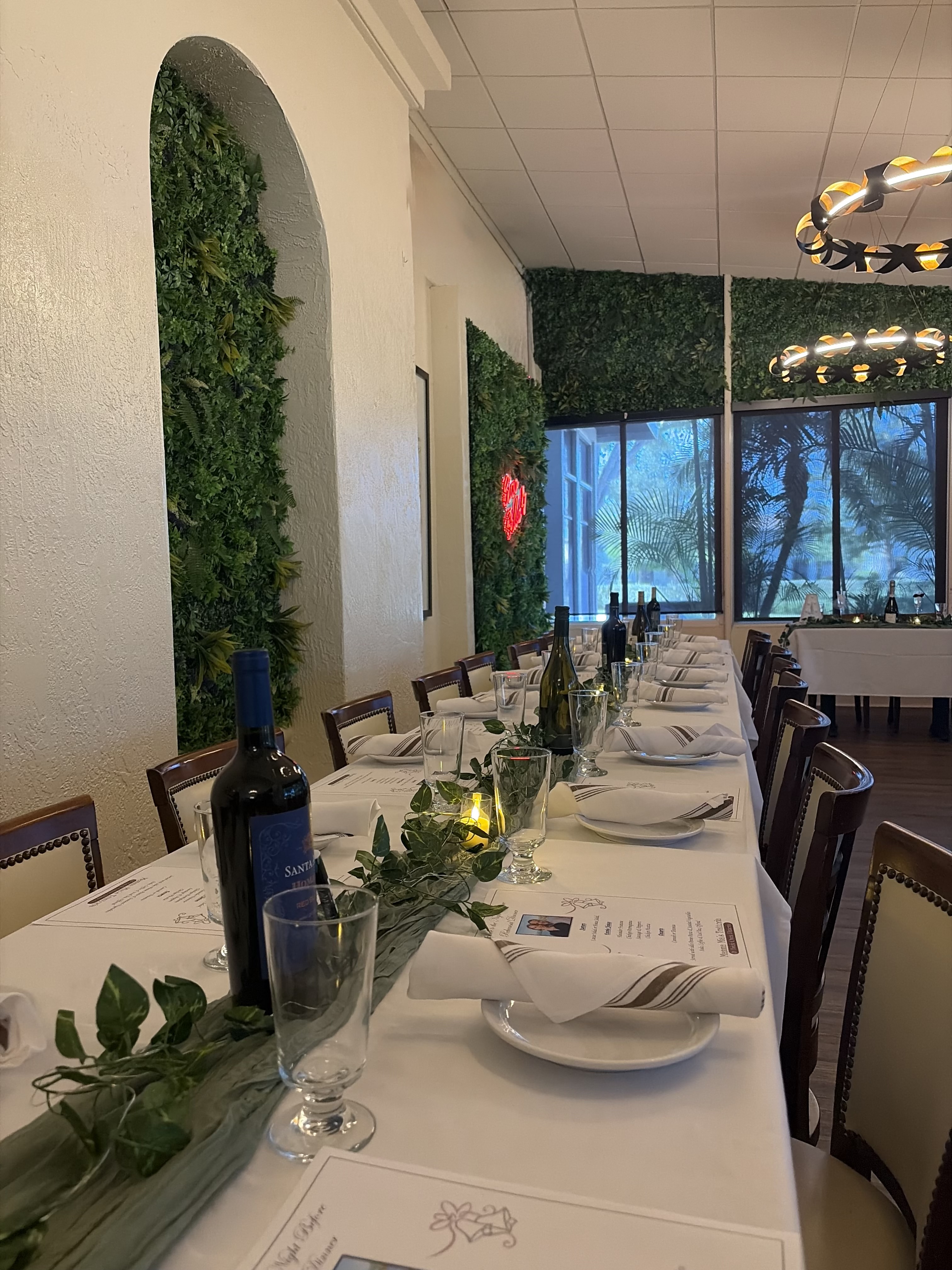 Long table set with bottles of wine, glasses and plates for a private event.