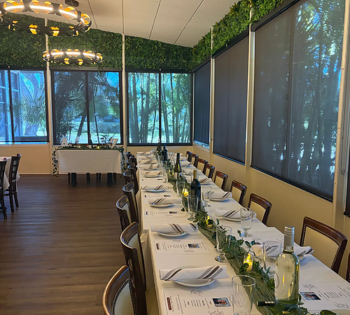 Side angle view of private event table with plates and wine bottles.