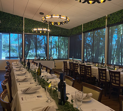 Side angle view of private event table with plates and wine bottles.
