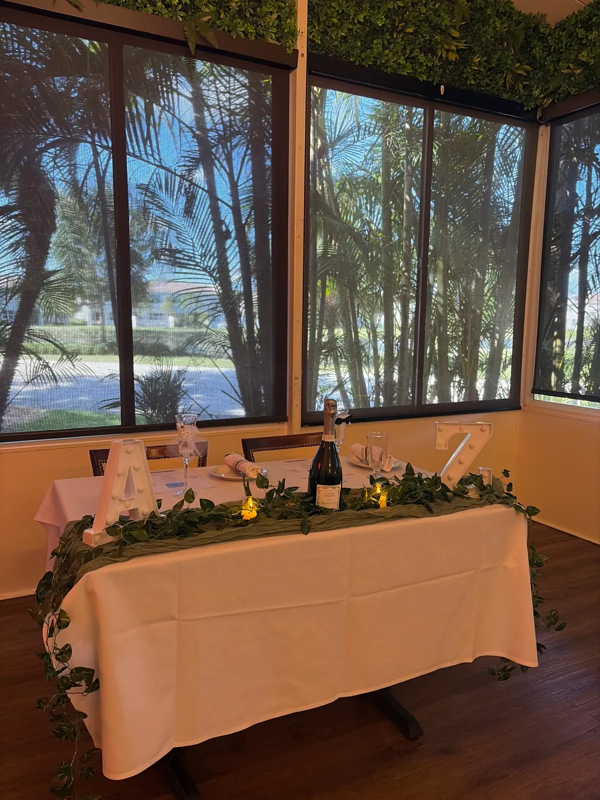 Long table set with bottles of wine, glasses and plates for a private event.