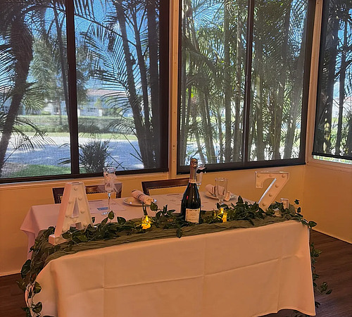 Long table set with bottles of wine, glasses and plates for a private event.